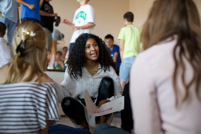 Lijana Kaggwa spricht in einer Gespraechsrunde auf Augenhoehe mit Jugendlichen in einer Schule.